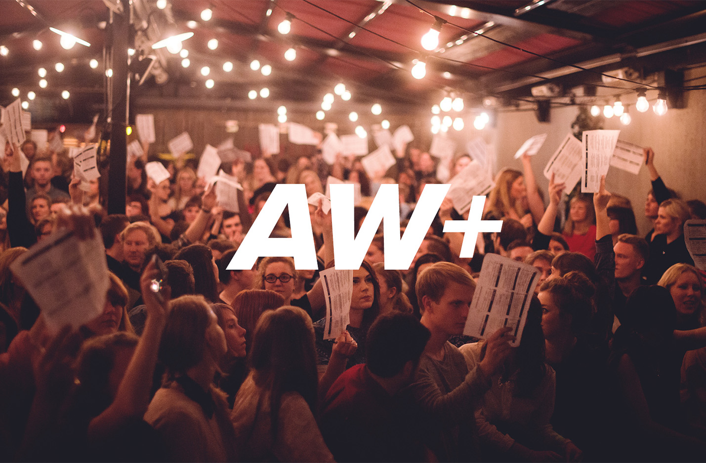 Klickbar bild AW+ Quiz. Bild på en folksamling som sträcker upp papper i luften. 