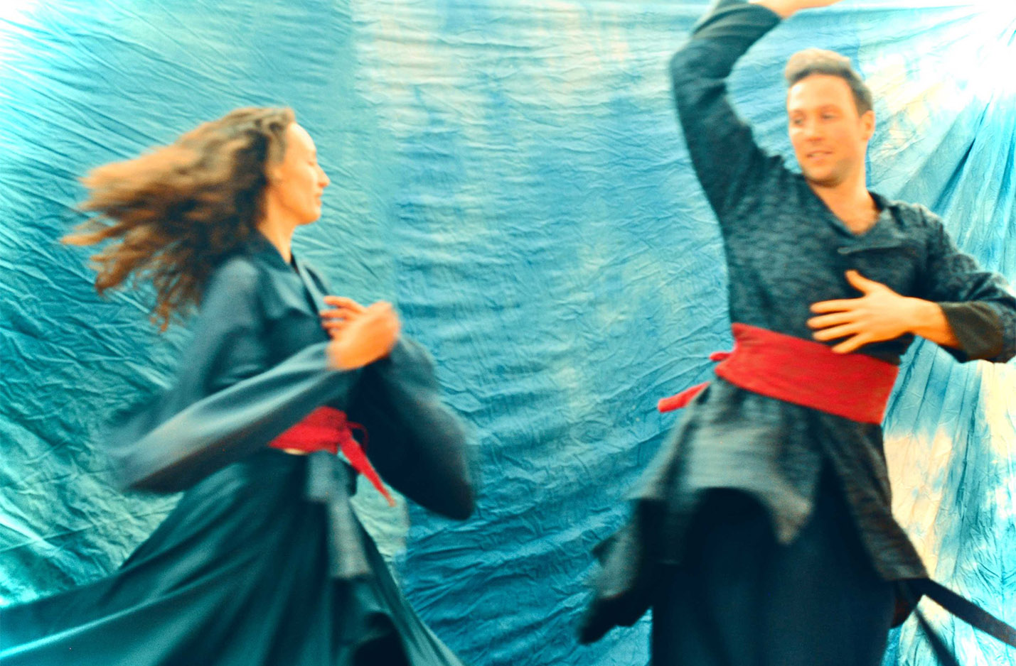 Klickbar bild Kalevalaskåpet. Två artister som dansar i blåa dräkt med rött skärp med ljusblå bakgrund